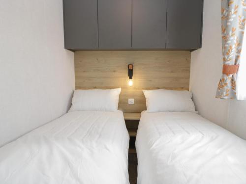 two beds in a small room with white sheets at Rowan in Denny