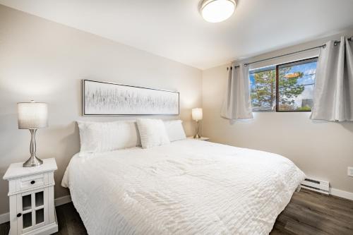 a white bedroom with a bed and a window at Modern Condo with Family-Friendly Hot Tub 102 in Blaine