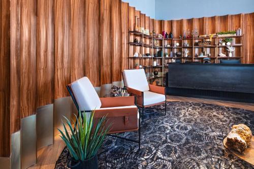 a lobby with two chairs and a piano at Vetta, Distrito Uno, Autograph Collection in Chihuahua