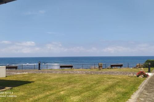 a view of the ocean from a park with benches at Edificio Tudor un mirador al Cantábrico in Comillas