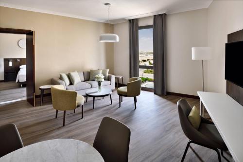 a living room with a couch and a table and chairs at Riyadh Airport Marriott Hotel in Riyadh