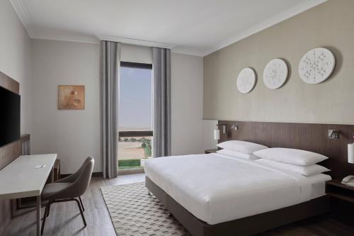 a bedroom with a large white bed and a desk and a table at Riyadh Airport Marriott Hotel in Riyadh