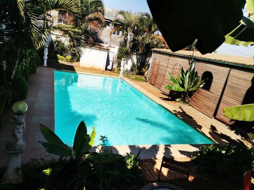 a blue swimming pool in a yard with trees at Hôtel La Kapila Ivato in Ivato