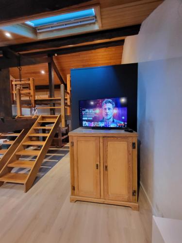 a tv on a cabinet in a room with stairs at Gites Rausa in Modave