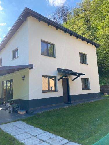 a large white house with a grass yard at Gura Râstii Holiday Home in Cluj-Napoca