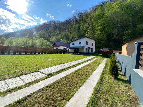 a field with a white house and a fence at Gura Râstii Holiday Home in Cluj-Napoca