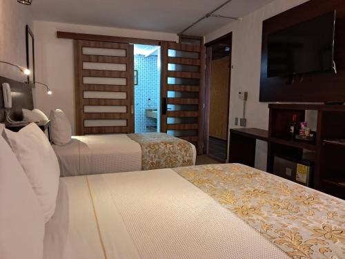 a hotel room with two beds and a television at La Floresta de Cite Hotel in Cite
