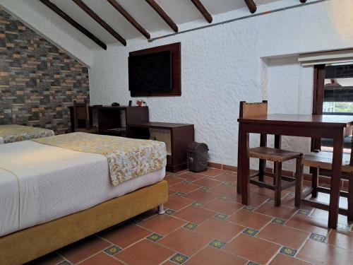 a bedroom with a bed and a desk and a table at La Floresta de Cite Hotel in Cite