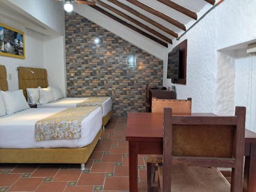 a bedroom with two beds and a table and a desk at La Floresta de Cite Hotel in Cite
