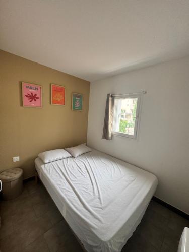 une chambre avec un lit blanc avec une fenêtre dans l'établissement Appartement résidence cap d'Agde, au Cap d'Agde