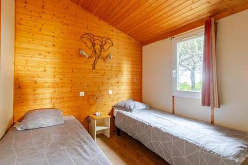 deux lits dans une chambre avec une fenêtre dans l'établissement Chalet Mer et Pins, à Agde