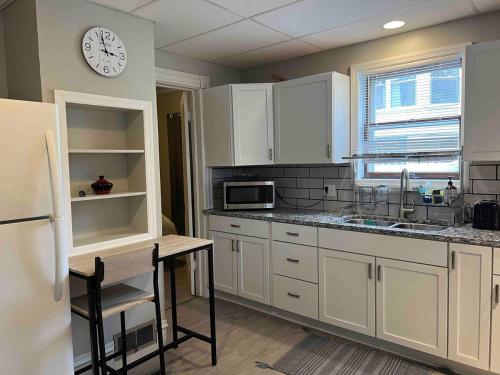 a kitchen with white cabinets and a clock on the wall at Apt A The Yellow Shuttered House in Sharon