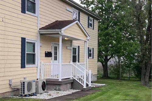 a house with a porch with a white railing at Apt 3 Comfortable and Convenient in Masury