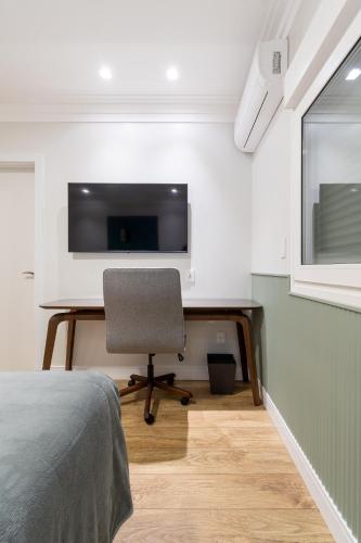 a bedroom with a desk with a chair and a tv at Hotel Kindermann Chapecó - Hotel Novo in Chapecó