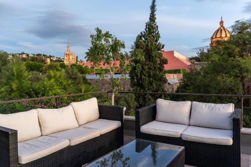 two wicker chairs and a coffee table on a balcony at Casa Quebrada, New 3BR Modern Home in Centro in San Miguel de Allende