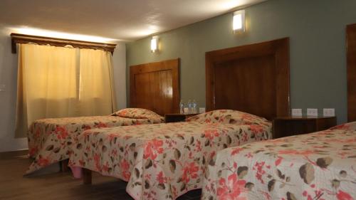 a hotel room with two beds with red and white sheets at La Casona de los Abuelos in Creel