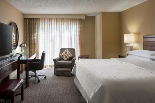 a hotel room with a bed and a chair and a desk at Sheraton Palo Alto Hotel in Palo Alto