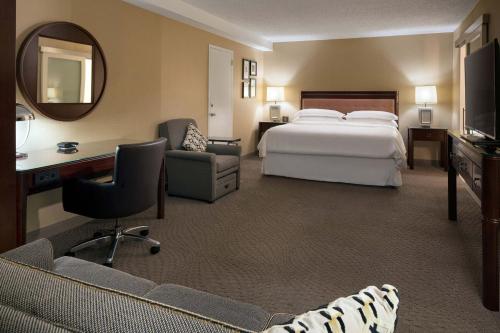 a hotel room with a bed and a desk and a mirror at Sheraton Palo Alto Hotel in Palo Alto