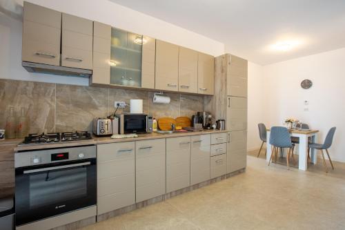 eine Küche mit weißen Schränken, einem Herd und einem Tisch in der Unterkunft ATENEO - TREVI 2 Rooms, Modern Apartment DeLuxe, BIG Terrace, Plus FREE Parking in Timişoara