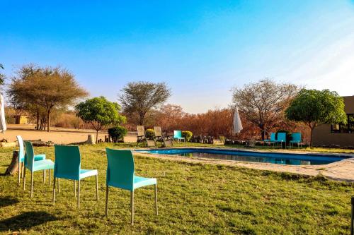 a group of chairs sitting in the grass near a pool at Destiny Blo Inn in Kachikau