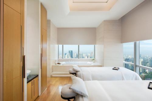 a white bedroom with a view of the city at The Westin Jakarta in Jakarta