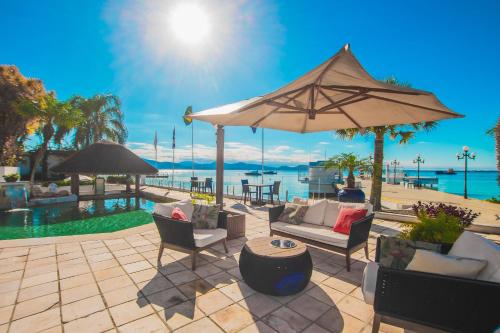 a patio with chairs and an umbrella next to the water at Hotel Villareal São Francisco do Sul in São Francisco do Sul