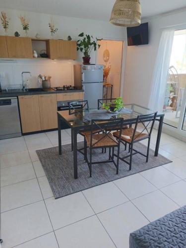 - une cuisine avec une table en verre et des chaises dans l'établissement Appartement aux portes de l'ocean et de la ria, à Plouharnel
