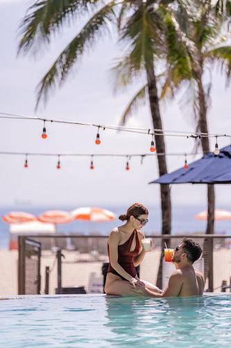 a man and woman sitting in a swimming pool at B Ocean Resort Fort Lauderdale Beach in Fort Lauderdale