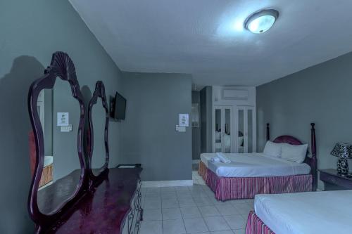 a hotel room with two beds and a mirror at Tamboo Resort in Negril