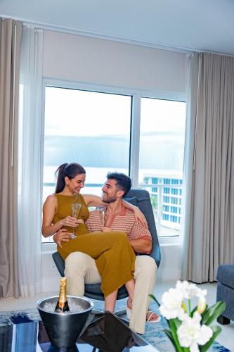 a man and woman sitting in a chair in a living room at B Ocean Resort Fort Lauderdale Beach in Fort Lauderdale