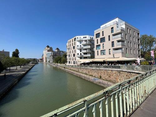 a river in a city with buildings and buildings at Studio de charme in Pantin