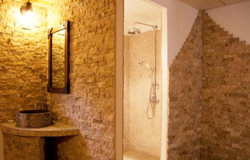 a bathroom with a shower and a stone wall at Domaine du Haut Jardin Hôtel & Chalets Spa Privé in Rehaupal