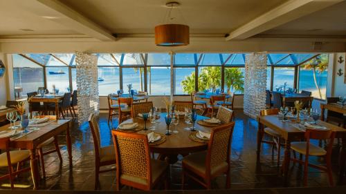 a restaurant with wooden tables and chairs and windows at Hotel Villareal São Francisco do Sul in São Francisco do Sul