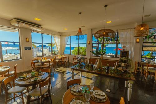 a restaurant with tables and chairs and large windows at Hotel Villareal São Francisco do Sul in São Francisco do Sul