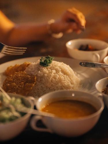 a plate of food with rice and a bowl of soup at Sundaras Infinity Jungle Resort in Dambulla