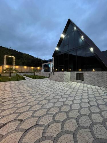 a large building with a cobblestone patio in front of it at Qafqaz Mountain Terrace İndoor Hot Pool in Gabala