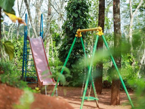 a swing set and a chair in a park at Serene Crest Resort in Mananthavady