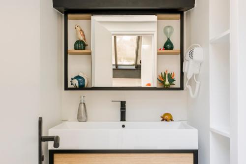 une salle de bain avec un lavabo blanc et un miroir dans l'établissement Relais Cocorico Artist Studio glass roof with AC, à Paris