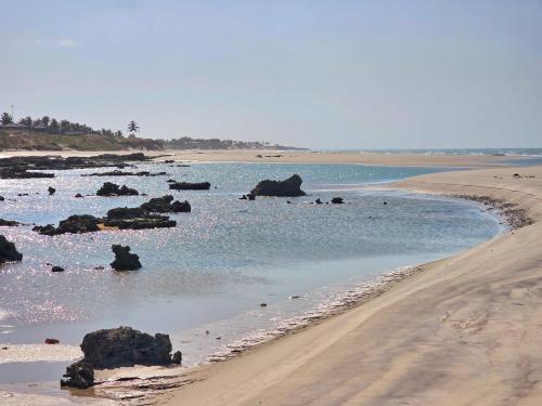 a beach with rocks in the water next to a beach at Chalés Mahalo J - Pontal de Maceió - Fortim in Fortim