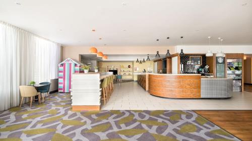 a living room with a kitchen and a dining room at Holiday Inn Brighton Seafront by IHG in Brighton & Hove