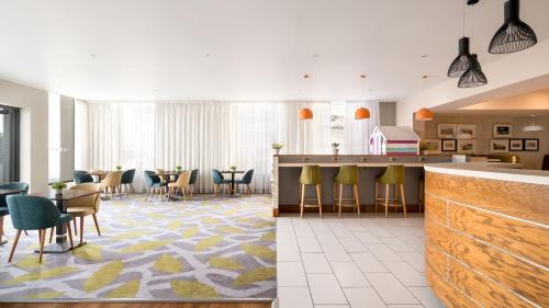 a lobby with a bar and tables and chairs at Holiday Inn Brighton Seafront by IHG in Brighton & Hove