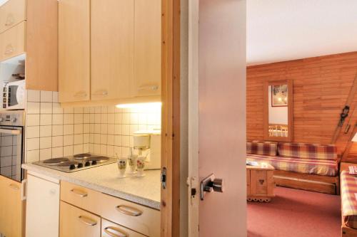 une cuisine avec des armoires blanches et un salon dans l'établissement Résidence Carroley A - 2 Pièces pour 5 Personnes 87, à Mâcot La Plagne