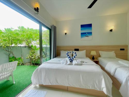 a bedroom with two beds and a large window at La Solara Villa in Ukulhas