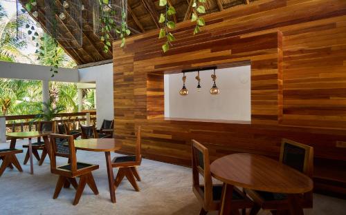 a restaurant with wooden walls and tables and chairs at Casa del Viento by ÓOL Hotels in Holbox Island