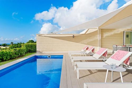 - une piscine avec des chaises longues à côté de la piscine dans l'établissement Westmoreland Hills 11-Whitehaven villa, à Saint James