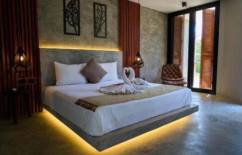 a bedroom with a bed with two swans on it at Casa del Viento by ÓOL Hotels in Holbox Island