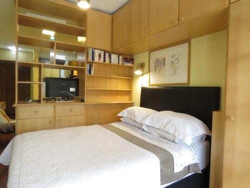 a bedroom with a bed and a tv and shelves at Kitnet Canela Plaza Serrana in Canela