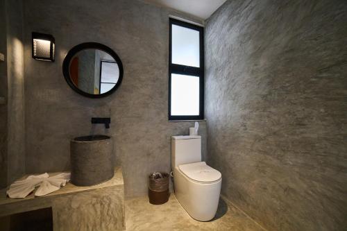 a bathroom with a white toilet and a mirror at Casa del Viento by ÓOL Hotels in Holbox Island
