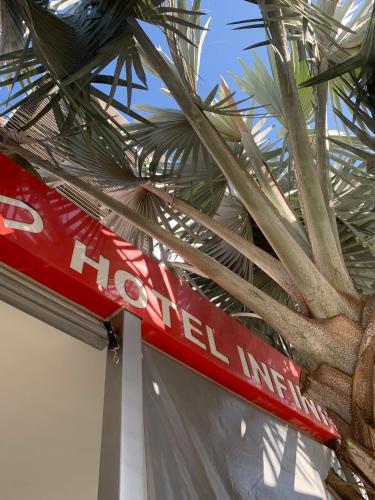 a red sign sitting next to a palm tree at Infinity Hotel in Goiânia