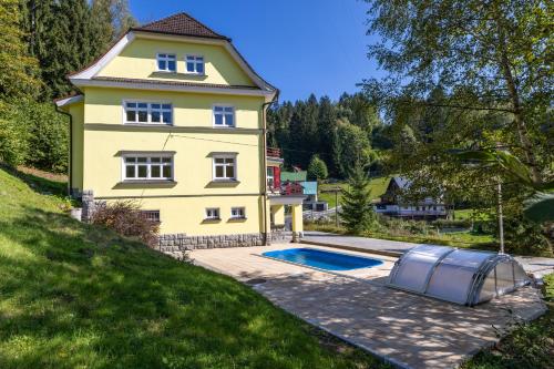 una casa amarilla con piscina frente a ella en Villa Weber Apartments, en Albrechtice v Jizerských horách